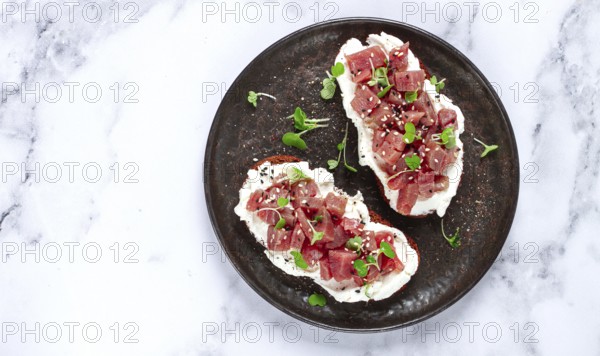 Sandwiches, rye bread with cream cheese, sliced tuna fillet with herbs, breakfast on a black plate, homemade