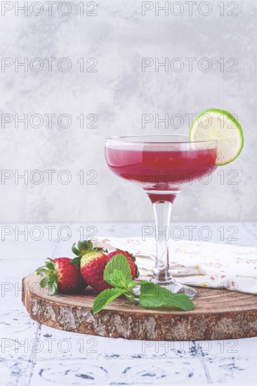 Refreshing cocktail in an elegant glass with lime and strawberries, sunshine, no people
