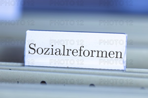 (Photomontage) Sign with the inscription SOCIAL REFORMS on a suspension file folder