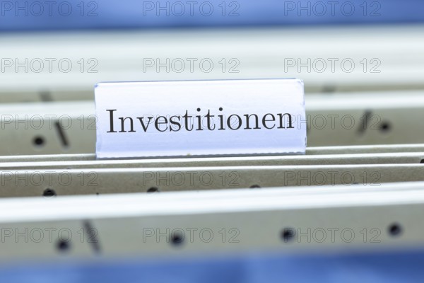 (Photomontage) Sign with the inscription INVESTMENTS on a suspension file folder