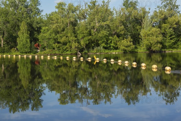 String of yellow cautionary navigation marker buoys on water surafce of river serving to warn, signal or indicate of a hazard beyond, Terrebonne, Quebec, Canada