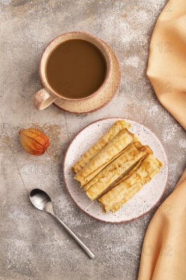 Waffles with caramel on brown concrete background and orange linen textile, cup of coffee, top view, flat lay, close up
