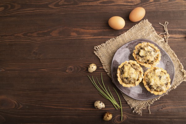Tartlets with meat and cheese on brown wooden background and linen textile. top view, flat lay, copy space