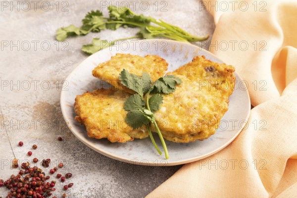 Fried crispy Chicken pancakes on brown concrete background and orange linen textile. side view, close up