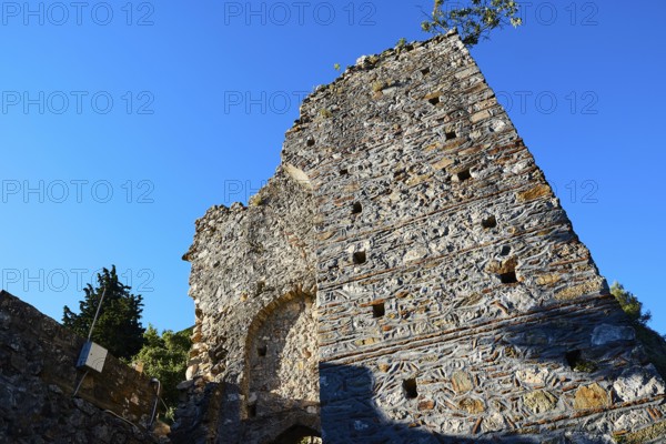 An ancient stone tower rises against a bright blue sky as an ancient structure, Mystras, Mistra, UNESCO World Heritage Site, Medieval Byzantine ruined city, northwest of Sparta, foothills of the Tyagetos Mountains, Peloponnese, peninsula, Greece
