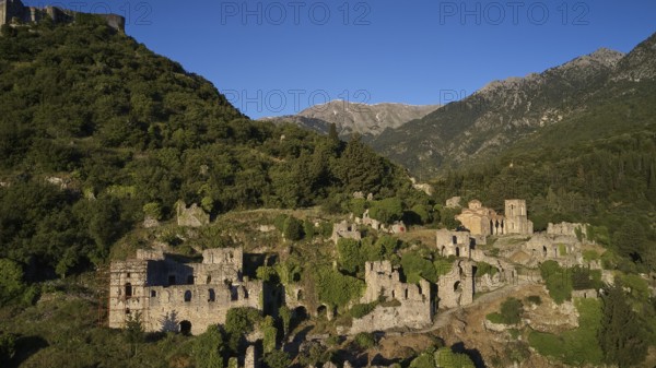 Drone shotRuins and buildings on a hill surrounded by green mountain landscape, including the church of Agia Sophia from the 14th century AD, Mystras, Mistra, UNESCO World Heritage Site, Medieval Byzantine ruined city, northwest of Sparta, foothills of the Tyagetos Mountains, Peloponnese, peninsula, Greece