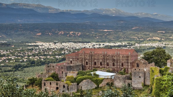 Byzantine palace of Mystras rises above a green landscape with mountains in the background, Mystras, Mistra, UNESCO World Heritage Site, Medieval Byzantine ruined city, northwest of Sparta, foothills of the Tyagetos Mountains, Peloponnese, peninsula, Greece