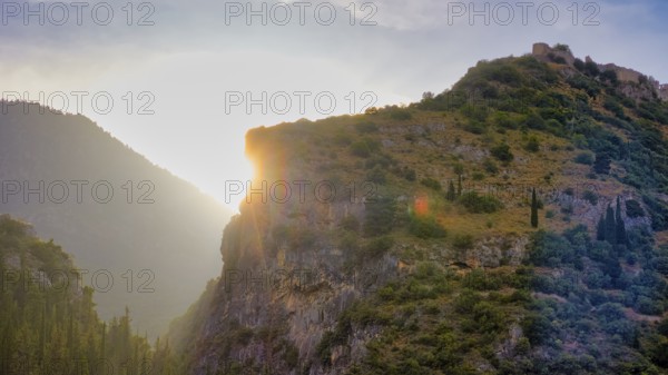 Byzantine castle from the 13th century AD, sun rays break through a rocky mountain landscape bathed in a warm light, Mystras, Mistra, UNESCO World Heritage Site, Medieval Byzantine ruined city, northwest of Sparta, foothills of the Tyagetos Mountains, Peloponnese, peninsula, Greece