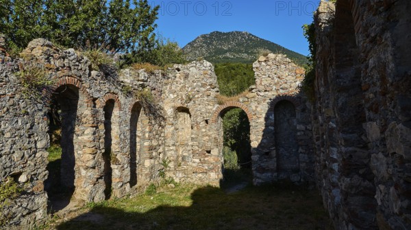 Stone ruins with arched passageways and mountain in the background, Mystras, Mistra, UNESCO World Heritage Site, Medieval Byzantine ruined city, north-west of Sparta, foothills of the Tyagetos Mountains, Peloponnese, peninsula, Greece