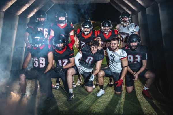 American football team poses united in helmets and pads, emerging from a smoky stadium tunnel under night lights, focused and ready for competition on the turf