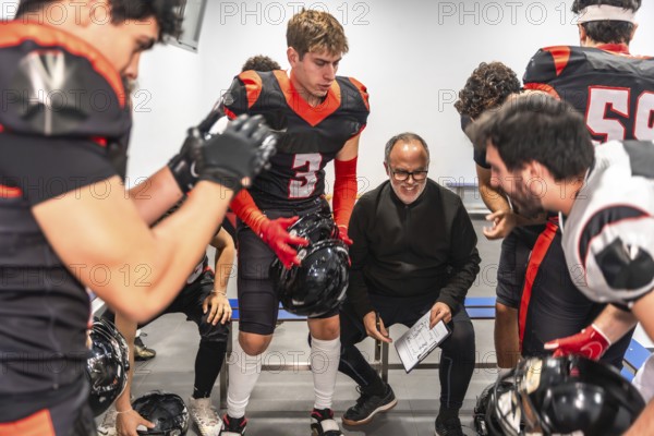 American football coach briefing players in a locker room, outlining strategy and tactics while team listens intently, focused and preparing for the upcoming game
