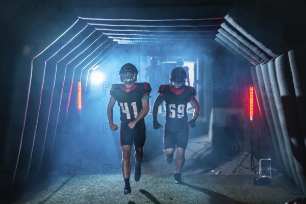 American football players burst from a smoky stadium tunnel in helmets and jerseys, running onto the field with determination and energy, ready for game day action and victory