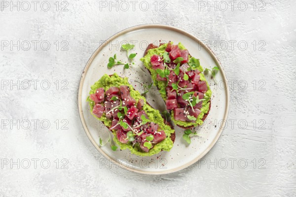 Toasts with fresh tuna and avocado, spread on black bread and sprinkled with microgreens, breakfast, healthy food
