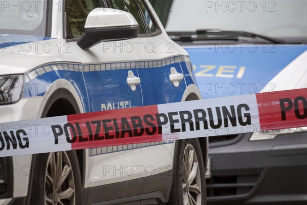 (Photomontage) Symbolic image of a police operation: police cordon in front of emergency vehicles