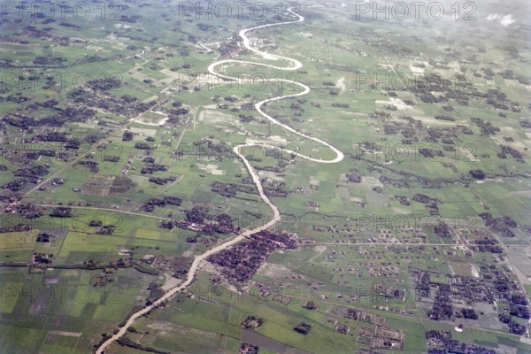 Captioned as 'aerial photo Saigon', meandering river in flat agricultural landscape of paddy fields, Vietnam, south east Asia c 1964