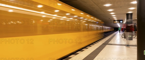 Dynamic scene of a Berlin underground in typical yellow colour, long exposure with blur effect, busy traffic junction at Unter den Linden station, Berlin, Germany