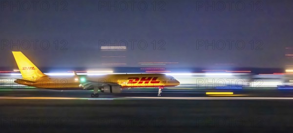 Stuttgart Airport in the early morning. DHL cargo plane landing. Light traces with motion blur. Stuttgart, Baden-Württemberg, Germany