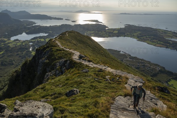 Woman with hiking poles walking up Rørsethornet stone stairs, with 3292 steps one of the longest continuous stone stairs in the world, Sherpat stairs or Midsund stairs or Midsundtrappene, Rørsethornet hike, Otroya or Otrøya island, Møre og Romsdal, Norway