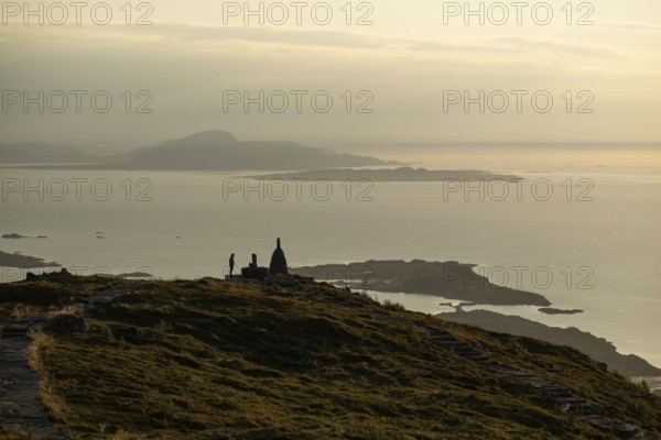 Woman standing next to cairn silhouette, Rørsethornet stone staircase, with 3292 steps one of the longest continuous stone staircases in the world, Sherpatreppe or Midsundtreppe or Midsundtrappene, Rørsethornet hike, evening mood, Otroya or Otrøya island, Møre og Romsdal, Norway