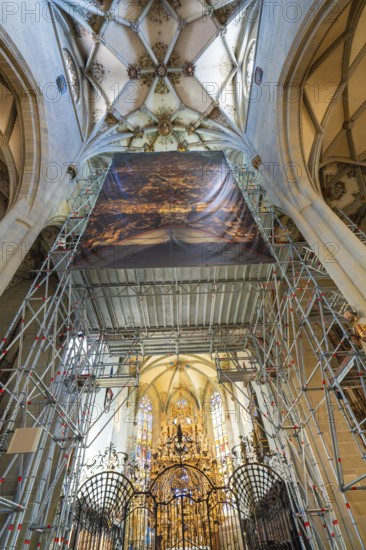 Magnificent church interior with scaffolding and golden decorations, covered by a painted banner, St Nicholas Minster, Überlingen, Lake Constance, Germany