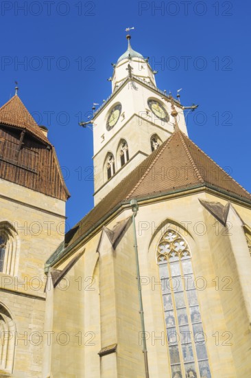 Gothic church tower with striking clock and pointed roofs in front of a bright blue sky, St Nicholas Minster, Überlingen, Lake Constance, Germany
