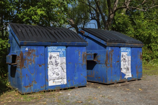 Blue metal with black plastic lid industrial size recycling bins for depositing glass, metal and plastic containers in, Ile des Moulins, Old Terrebonne, Quebec, Canada