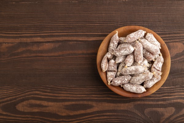Small smoked Chicken sausages in wooden bowl on brown wooden background. top view, flat lay, copy space