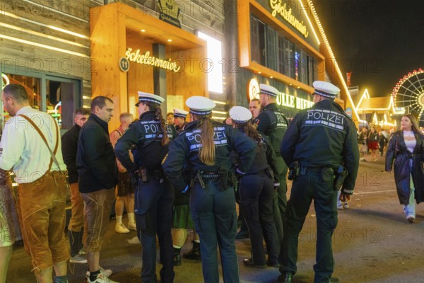Police officers monitor the marquee area at night and ensure safety among the visitors, Cannstatter Wasen folk festival, Stuttgart, Germany