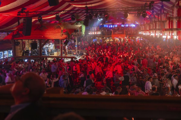 A well-attended marquee with red lights and a cheerful party atmosphere, Cannstatter Wasen folk festival, Stuttgart, Germany