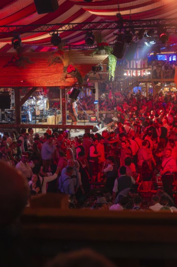 Crowded hustle and bustle in an atmospherically illuminated beer tent at the festival, Cannstatter Wasen folk festival, Stuttgart, Germany