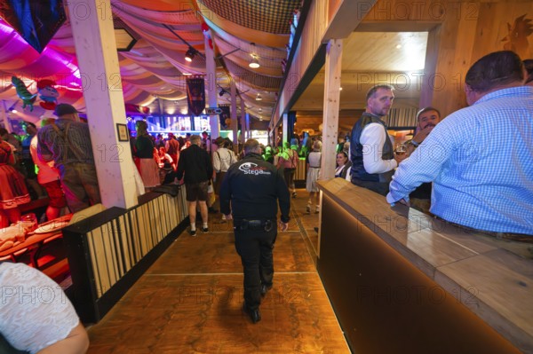 Security guard in a well-filled marquee with atmospheric lighting, Cannstatter Wasen folk festival, Stuttgart, Germany