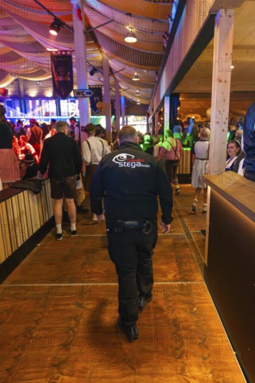 Security guard in a well-attended beer tent with festival decorations, Cannstatter Wasen folk festival, Stuttgart, Germany