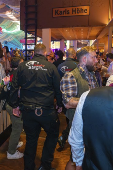 Security guards in a busy marquee during a party, Cannstatter Wasen folk festival, Stuttgart, Germany