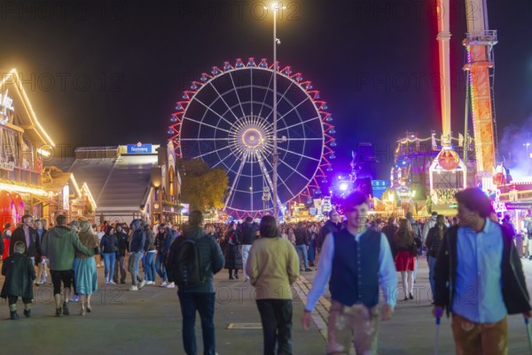 Night market with a brightly lit Ferris wheel and many visitors, Cannstatter Wasen fair, Stuttgart, Germany