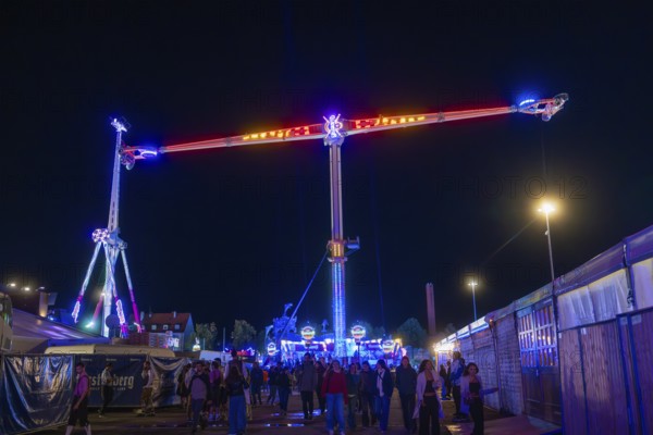 Lively funfair at night with colourful lights and many visitors, Cannstatter Wasen funfair, Stuttgart, Germany