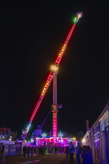 A towering illuminated ride at night at a funfair, Cannstatter Wasen fair, Stuttgart, Germany