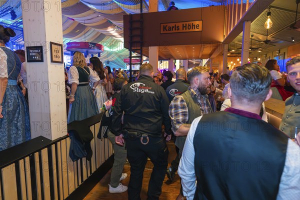 Lively beer tent with security guards and festive atmosphere, Cannstatter Wasen folk festival, Stuttgart, Germany