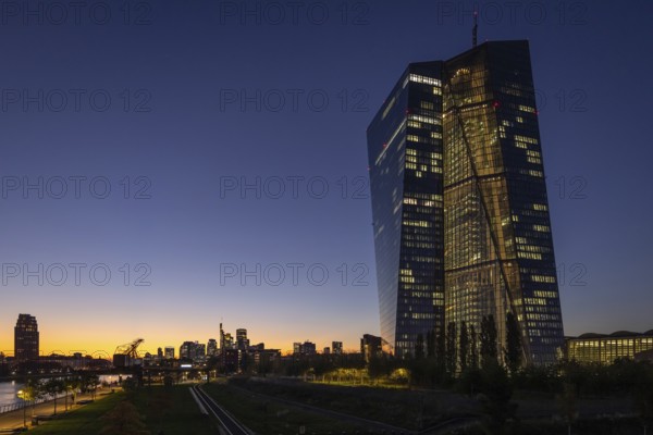 The lights of the European Central Bank (ECB) and the Frankfurt banking skyline glow in the evening, Frankfurt am Main, Hesse, Germany