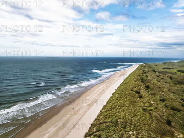 Beach and Dunes over Bamburgh Castle from a drone, Northumberland, Northeast Coast, England, United Kingdom