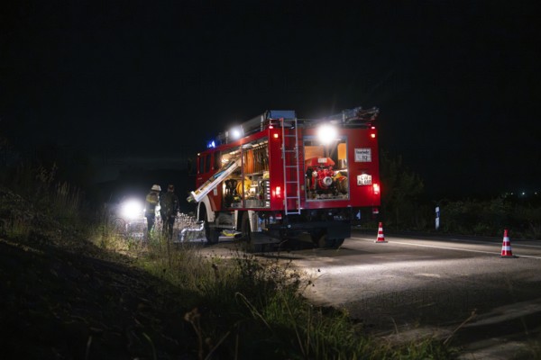 Fire engine with bright lights standing on a road at night, surrounded by traffic cones, fire brigade exercise in the new construction tunnel of the Hermann Hesse railway, Ostelsheim, Calw district, Germany