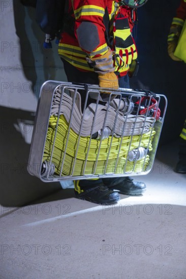 Firefighter holding hose carrier basket in illuminated area, ready for action, firefighting exercise in the new construction tunnel of the Hermann Hesse railway, Ostelsheim, district of Calw, Germany