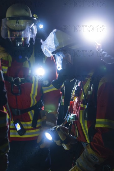Two firefighters in protective clothing and breathing masks with torches in action at night, fire drill in the new construction tunnel of the Hermann Hesse railway, Ostelsheim, district of Calw, Germany