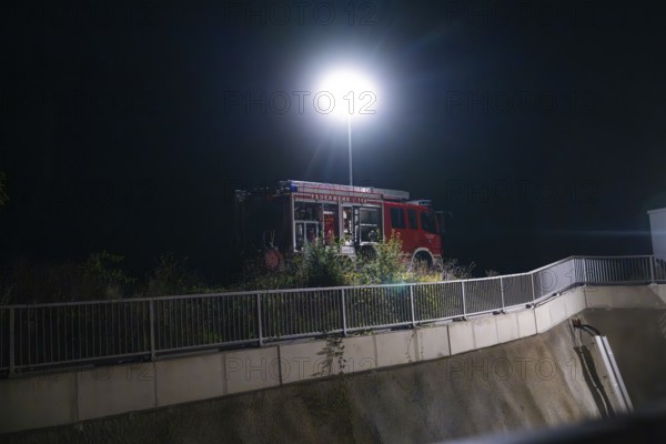 Fire engine under a street lamp next to a fence and plants at night, fire drill in the new construction tunnel of the Hermann Hesse railway, Ostelsheim, district of Calw, Germany