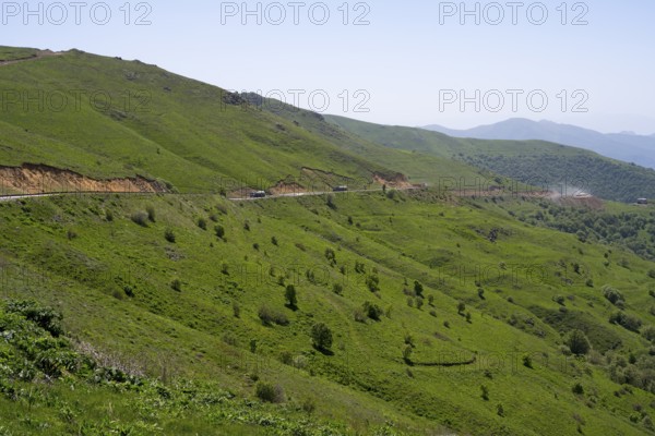 Road runs along the green hills in a landscape with mountains, at the highest pass in Armenia, Meghri Pass, Tashtun Pass, Syunik Province, Syunik, Armenia
