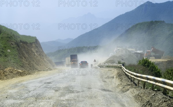 Dusty road with construction site in mountainous landscape with construction vehicles and lorries, connecting road M2 at the highest pass of Armenia, Meghri Pass, Tashtun Pass, Syunik province, Syunik, Armenia, Asian road with cars and construction site in a mountainous area