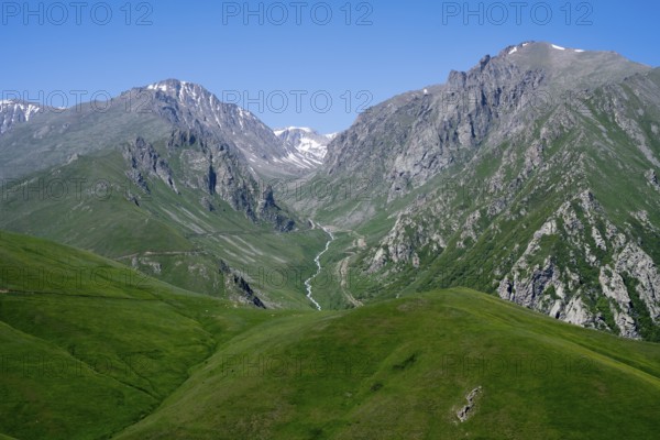 Green hills and a deep valley with mountains under a clear sky, at the highest pass in Armenia, Meghri Pass, Tashtun Pass, Syunik Province, Syunik, Armenia