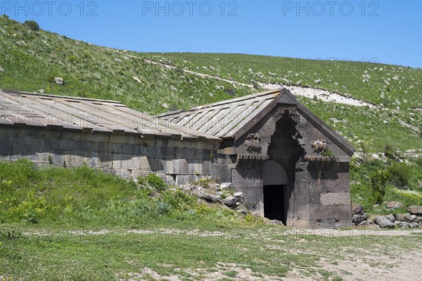 Stone building in a rural setting with a green hill in the background, Orbelian's Caravanserai, Selim Caravanserai, located at the Vardenyats Pass or Selim Pass, Vayots Dzor Province, Armenia