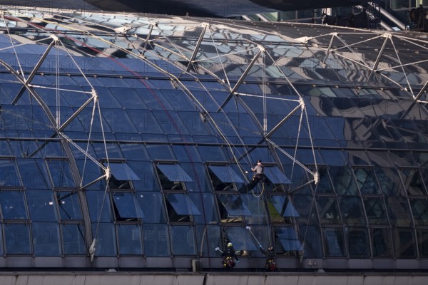 Three male glass cleaners cleaning a glass roof at Berlin Central Station, Berlin, Germany
