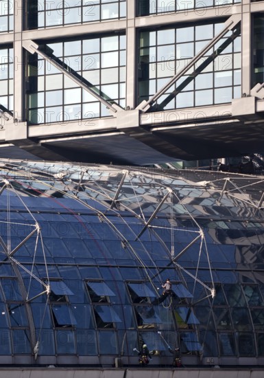 Three male glass cleaners cleaning a glass roof at Berlin Central Station, Berlin, Germany