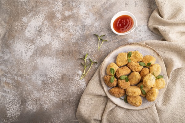 Fried crispy Chicken Nuggets with ketchup, microgreen on brown concrete background and linen textile. top view, flat lay, copy space